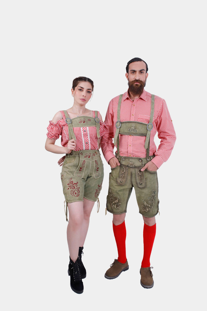 A couple wearing traditional German clothing with suspenders. The woman is dressed in a red and white checkered off-shoulder top with olive embroidered shorts and with suspenders attached to her shorts. The man is in a matching red and white checkered shirt, olive embroidered shorts, red knee-high socks, brown shoes, and suspenders. They are standing side by side, looking straight ahead