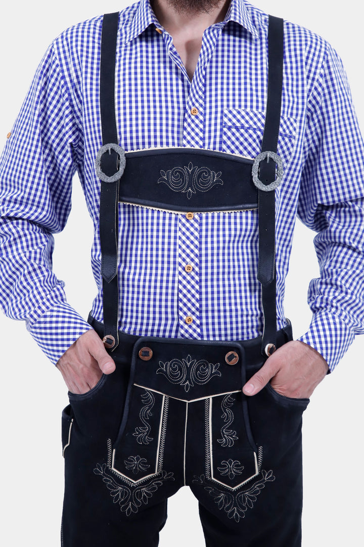 A close-up view of the front of the Brandburg Bundhosen Outfit, worn by a man. The focus is on the intricate embroidery on the front of the pants, the detailed buttons on the suspenders, and the decorative belt buckle. The leather-like material and traditional Bavarian styling are clearly visible.