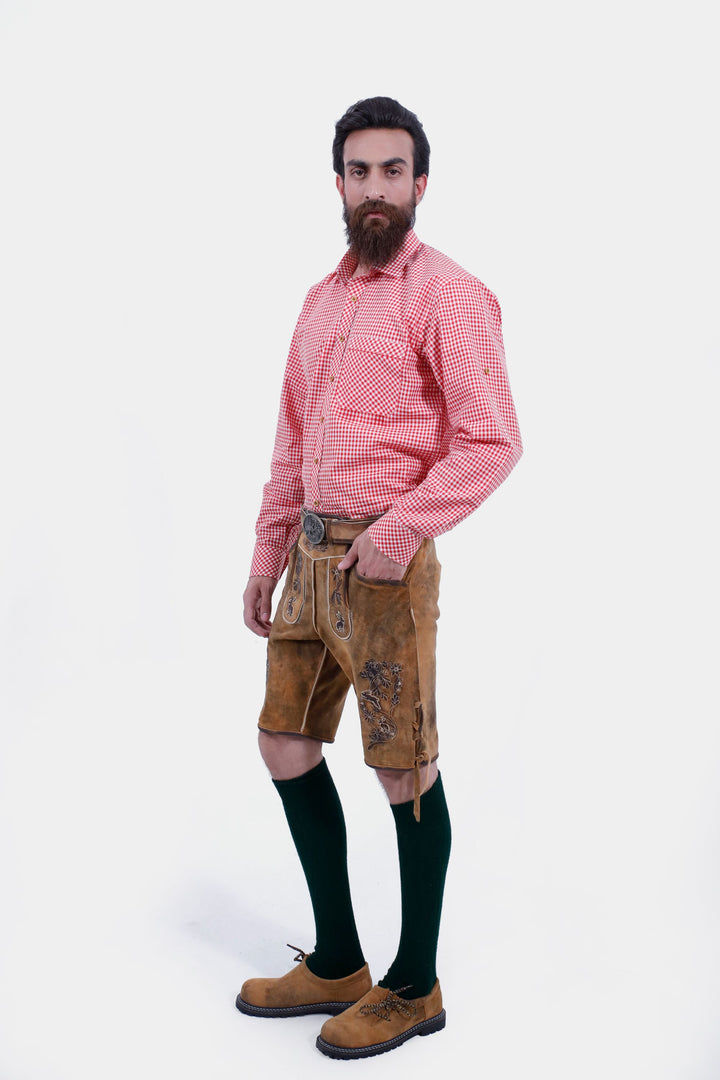 Angled side view of a man wearing Chiemsee Lederhosen and a pink checkered shirt, highlighting the intricate embroidery on the leather shorts.