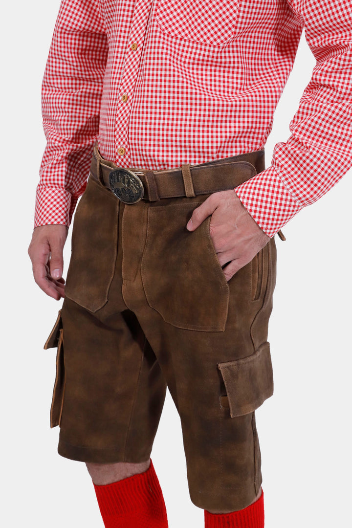 Close-up of the DJ Ötzi Cargo Lederhosen, highlighting the side pockets and belt with a decorative buckle, worn with a red checkered shirt.