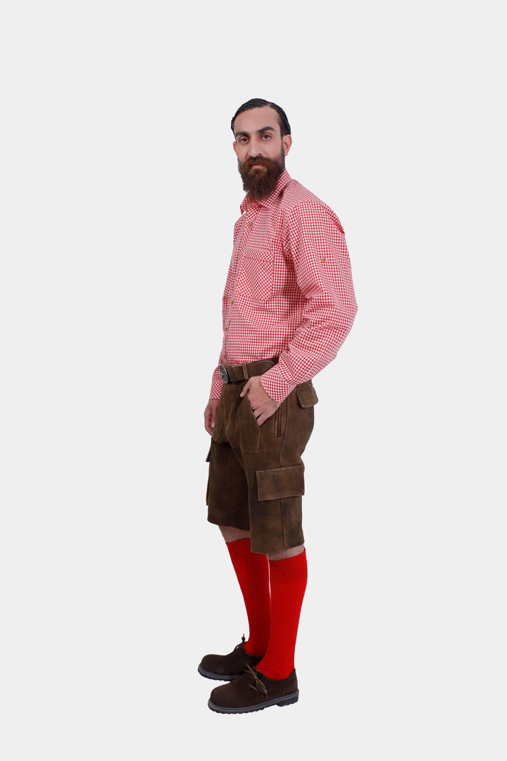 Side profile of a man in DJ Ötzi Cargo Lederhosen, with his hand in the pocket, wearing a red checkered shirt and red socks.