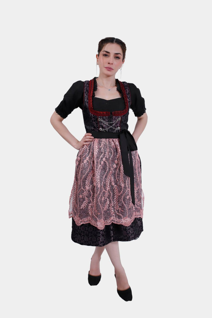 Full-length view of a woman wearing a traditional Dirndl Franka, featuring a pink lace apron over a black skirt.