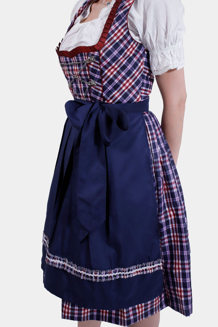 Side view of a woman in Dirndl Hilker, emphasizing the full navy skirt and beautifully tied sapphire apron.