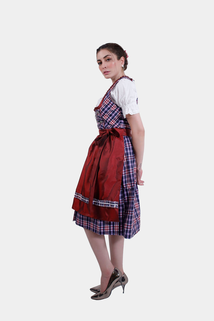 Model wearing the Dirndl Zsa Inci, featuring a rich crimson bodice with intricate embroidery, a matching apron, and a white blouse