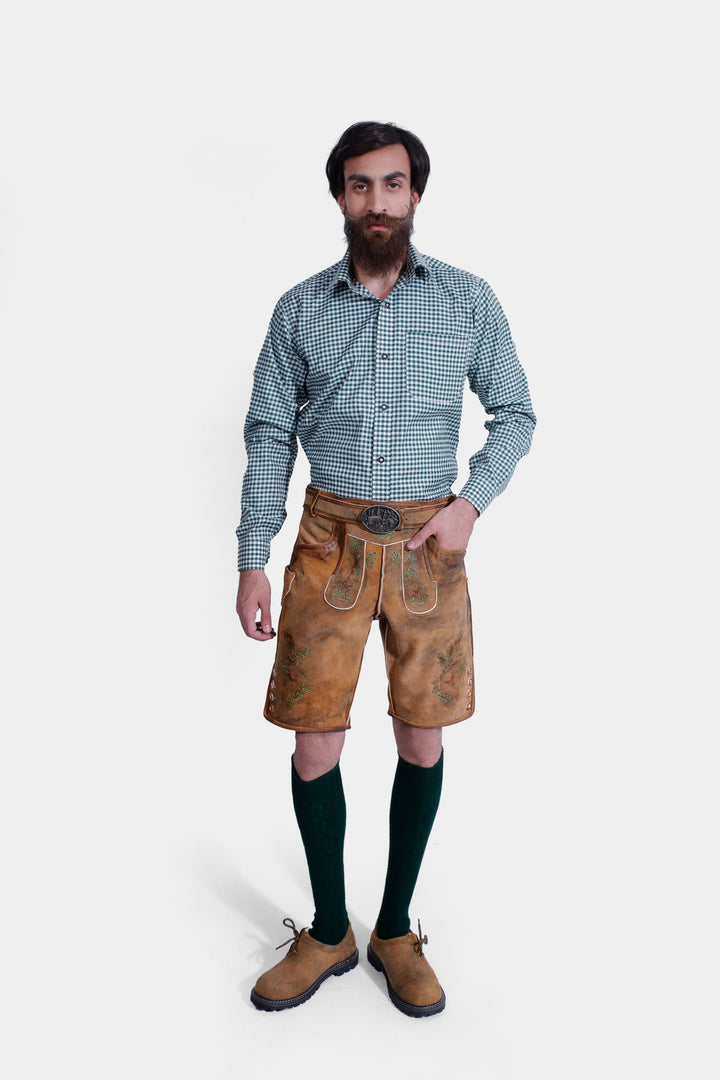 A man with a beard wearing the Durant Lederhosen Outfit, including a green checkered shirt, brown leather Lederhosen with green embroidery, green knee-high socks, and brown shoes. herren trachten lederhose kurz