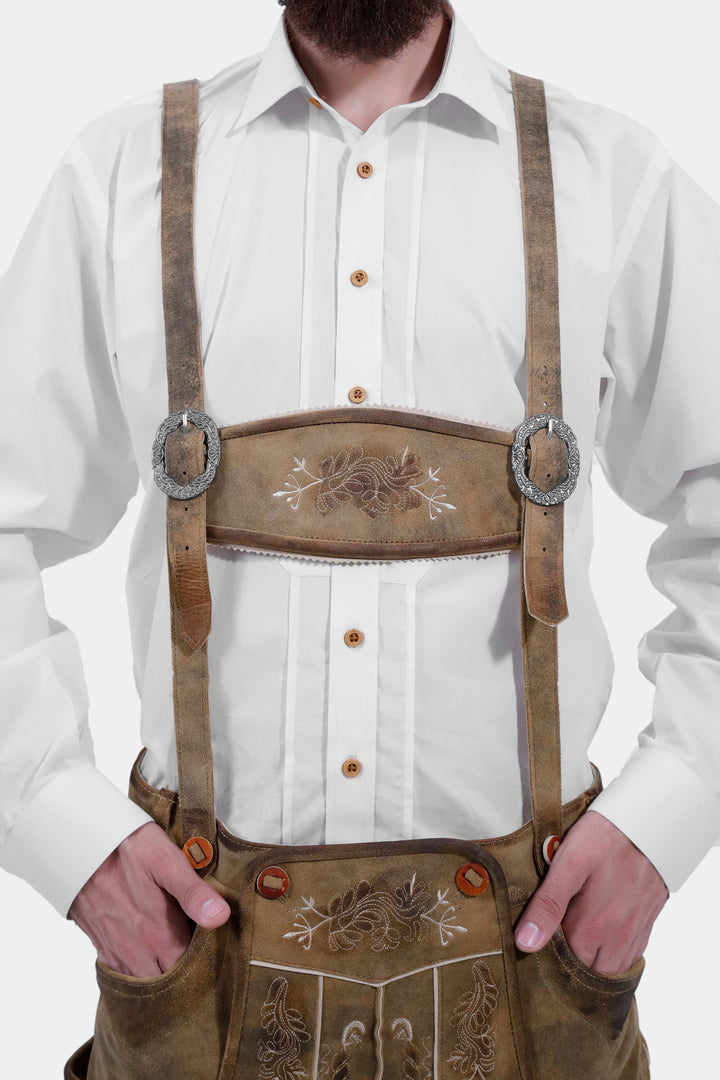 Close-up view of the chest area of a man wearing the Edinburgh Castle Bundhosen with suspenders, focusing on the embroidered front panel, paired with a white shirt