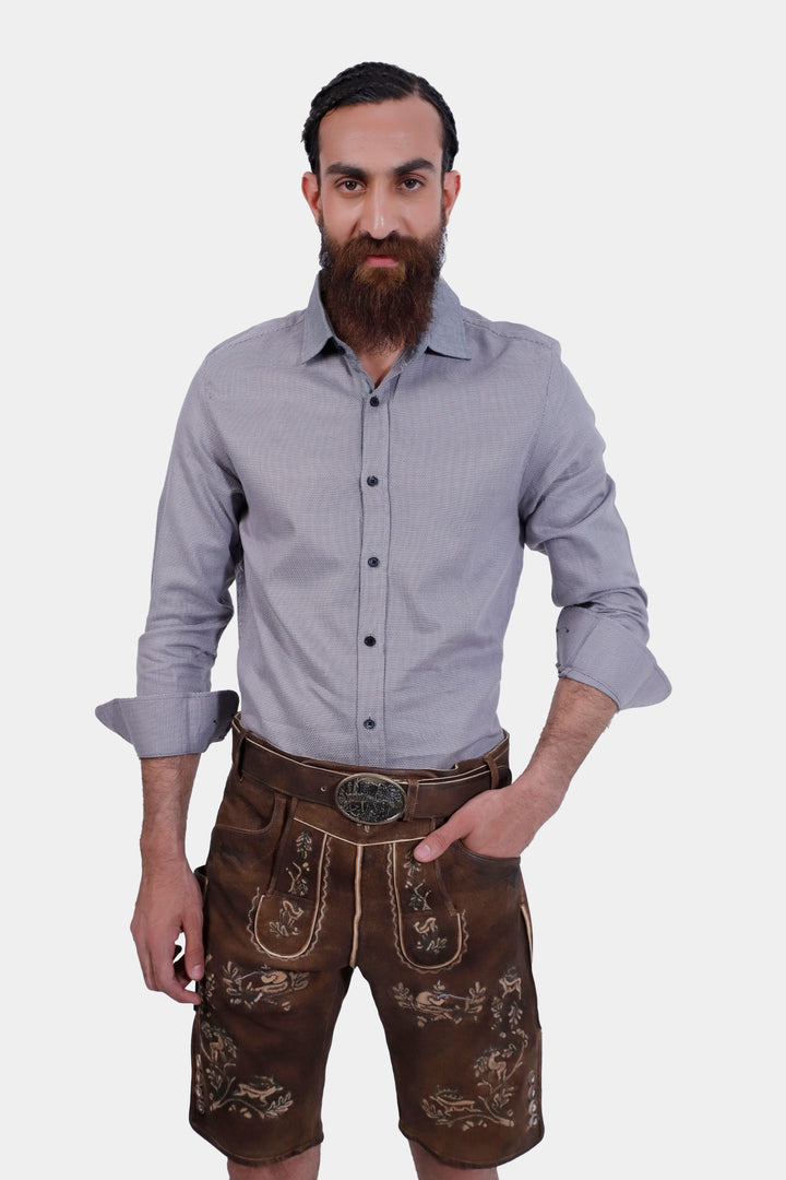 Man posing in Ein Prosit Lederhosen, hands in pockets, showcasing the front view of brown leather shorts with detailed embroidery.