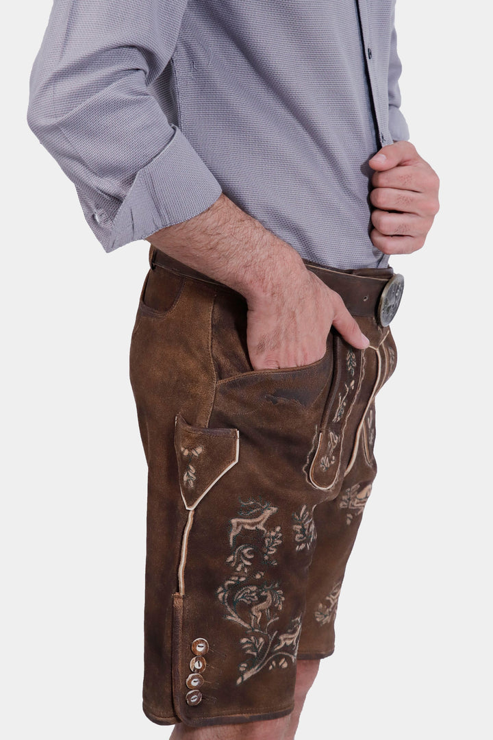 Side profile of a man wearing Ein Prosit Lederhosen, highlighting the detailed embroidery on the brown leather shorts and the belt buckle.