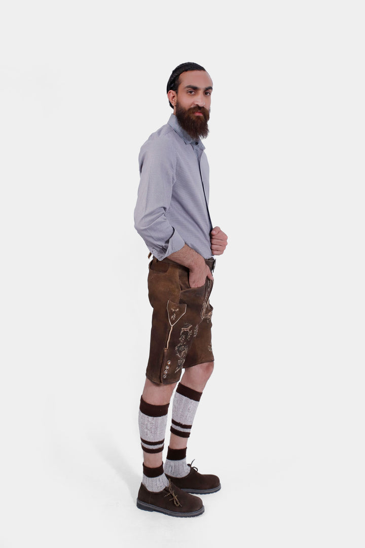  Side view of a man wearing Ein Prosit Lederhosen, with one hand in pocket, highlighting the side embroidery and traditional buttons on the leather shorts.