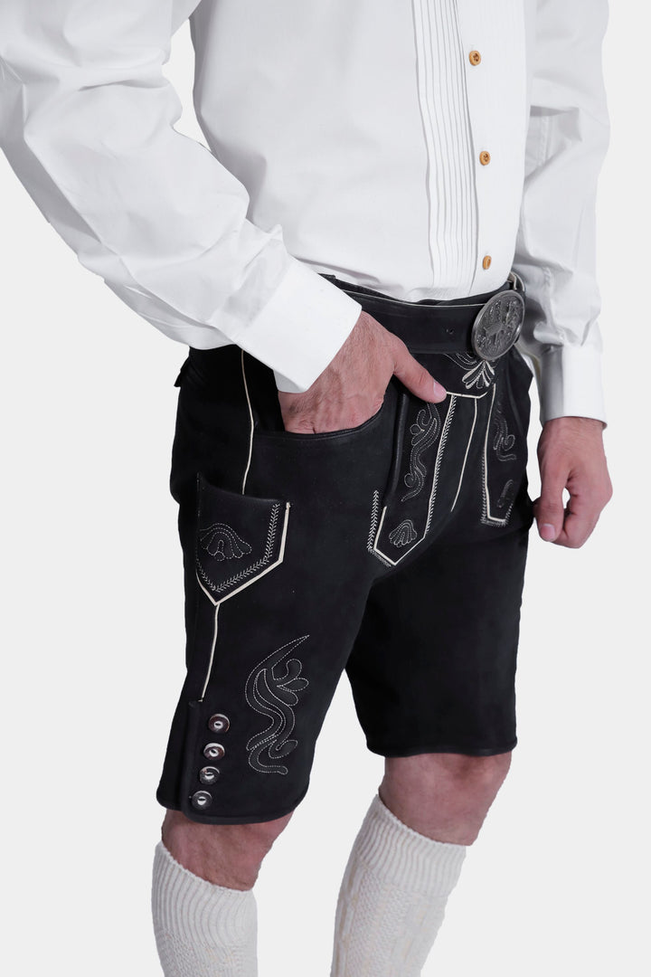 Detailed view of the Elgort Lederhosen Outfit, focusing on the black leather Lederhosen with white embroidery, the front flap, and the belt, along with the white shirt and knee-high socks.