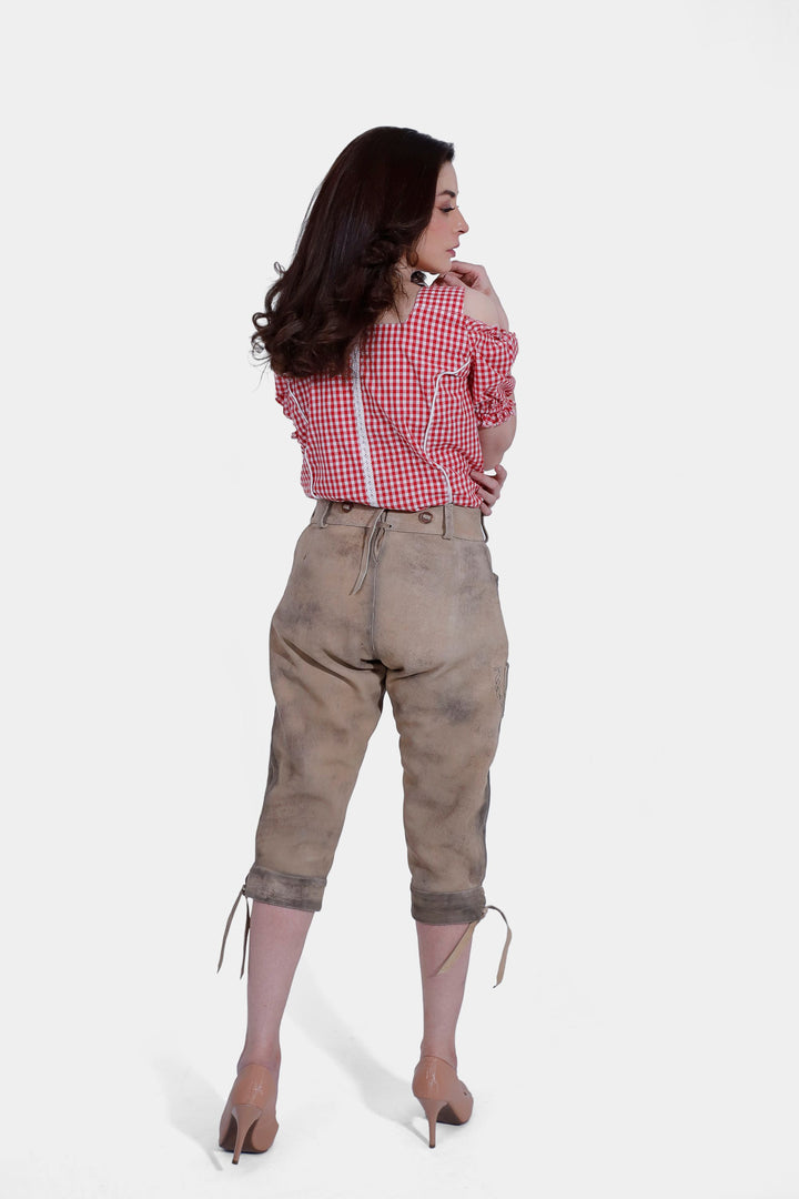 Back view of a woman wearing a red and white checkered blouse and light brown lederhosen, showing the fit and rear design of the outfit.