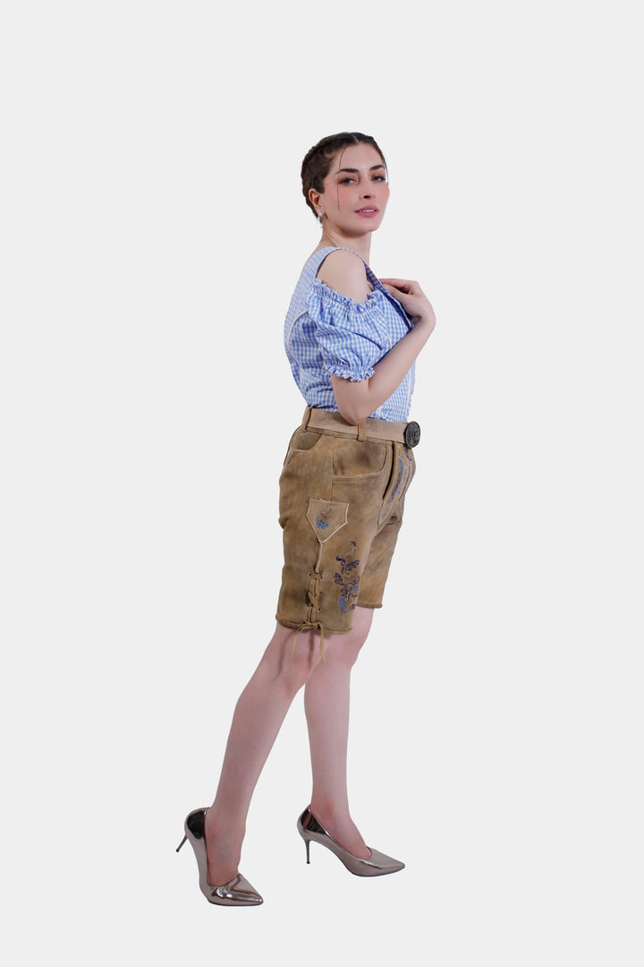 Woman striking a pose in Helene Lederhosen, with one hand on hip and the other touching shoulder, displaying detailed embroidery.