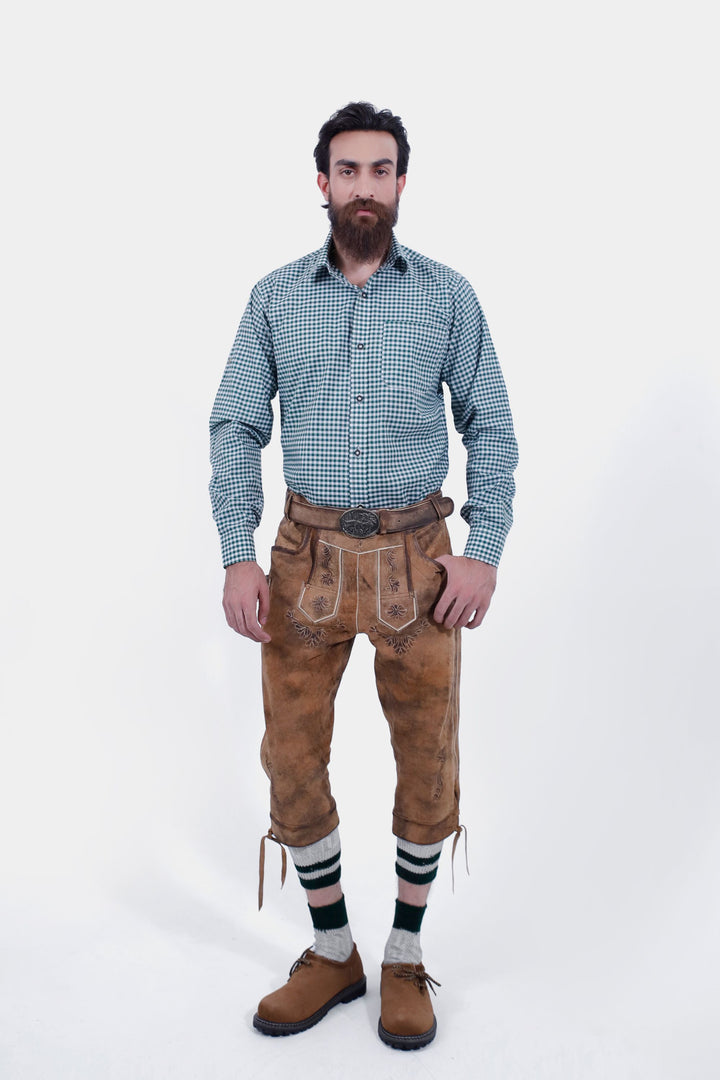 Man wearing a green checkered shirt and Hesse Bundhosen, standing straight. The brown leather pants have detailed floral embroidery on the front, side pockets, and are paired with traditional Bavarian shoes and green-striped socks. kniebundlederhose herren​