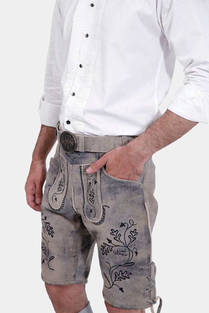 Close-up of Hofburg Lederhosen showcasing detailed embroidery, man's hand in pocket.