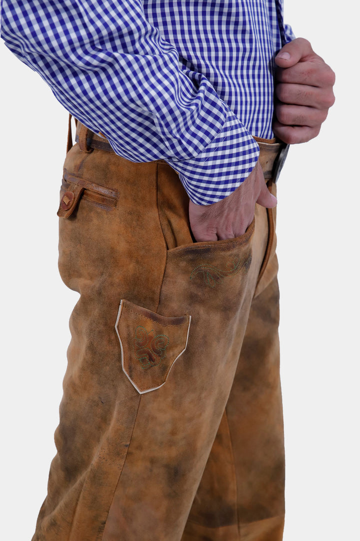 A close-up view of a man wearing a blue and white checkered shirt and Humboldt Long Lederhosen, with his hand resting in the front pocket of the pants.