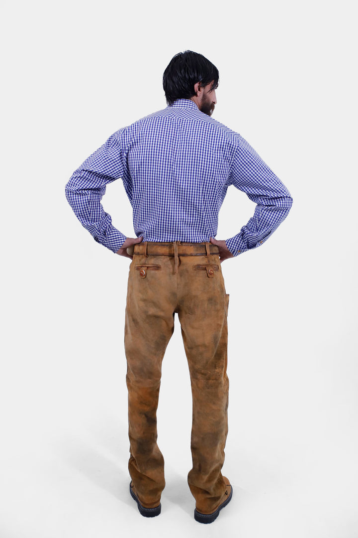 A back view of a man wearing a blue and white checkered shirt and Humboldt Long Lederhosen, showcasing the details on the back of the pants.