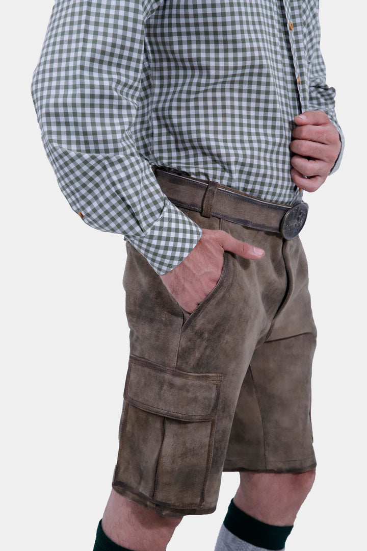 Side view of a man in Klimt Cargo Lederhosen and a gray checkered shirt, showing the fit and pockets of the traditional Bavarian leather shorts.