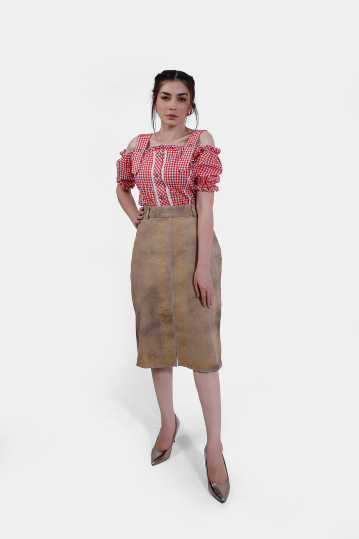 Model wearing a Kollwitz Lederhosen Skirt in sandy tan buck skin leather, paired with a red and white checkered blouse, front view. lederröcke für damen​, lederrock beige, lederrock lang