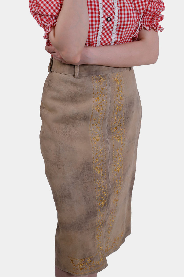 Close-up of the Kollwitz Lederhosen Skirt in sandy tan buck skin leather, showcasing intricate embroidery details, with a red and white checkered blouse.