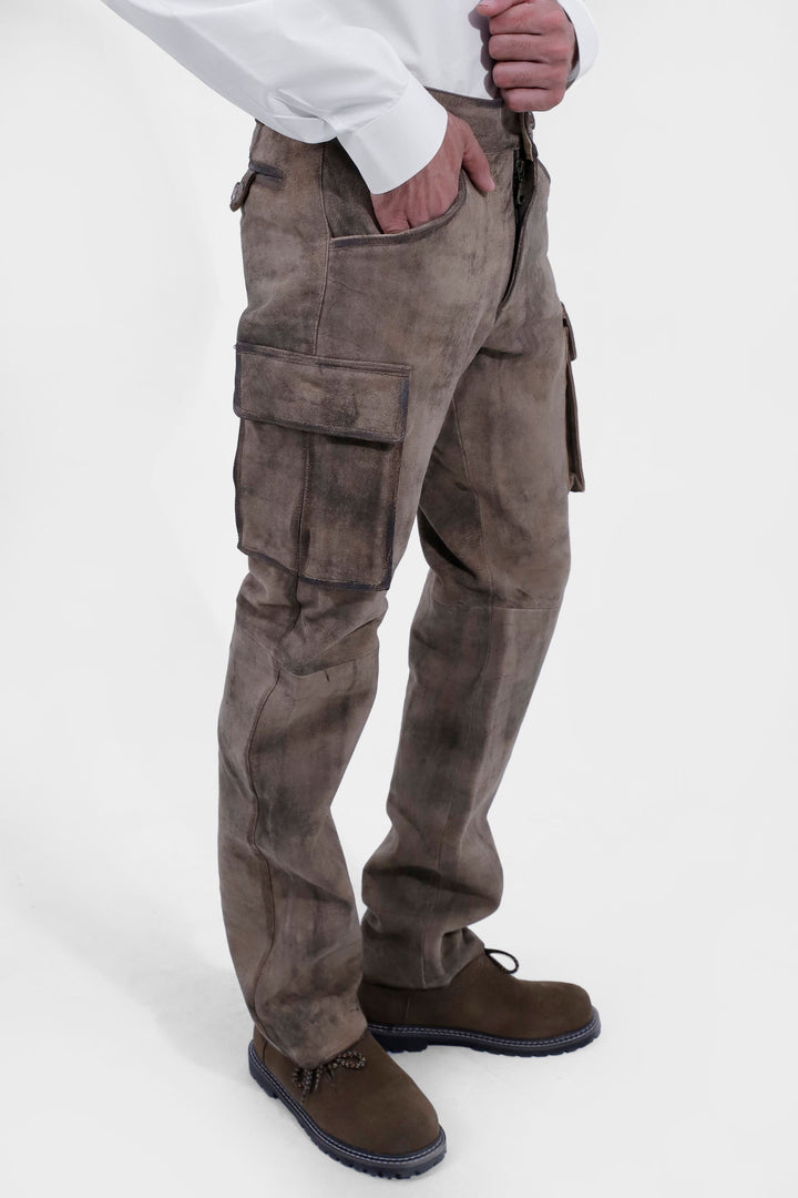 Close-up of the lower half of a person wearing Königssee Cargo Lederhosen Long Pant with detailed stitching and cargo pockets, paired with brown leather shoes.