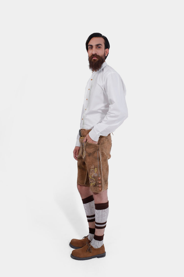 A side profile of the man wearing Leavenworth lederhosen, showing the detailed embroidery and the white shirt with wooden buttons.