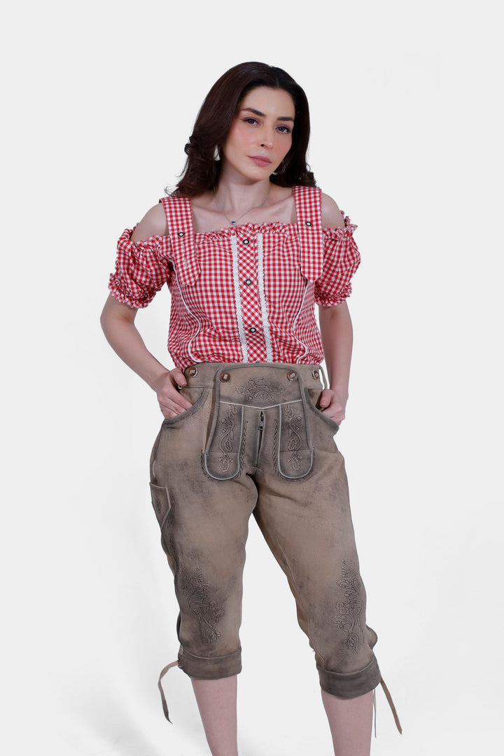 Close-up front view of the woman wearing a red checkered blouse and brown leather lederhosen, focusing on the blouse and the detailed embroidery on the pants.