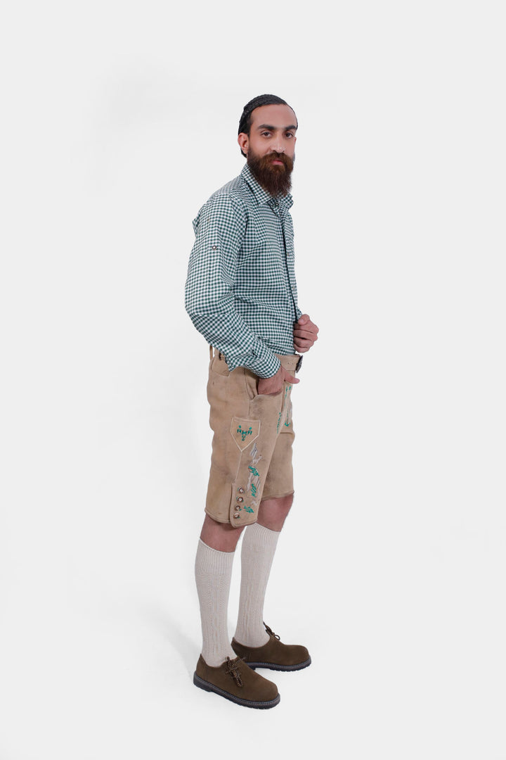 Side profile of the man wearing the Luther Lederhosen, showcasing the embroidery and horn buttons on the leg cuffs.