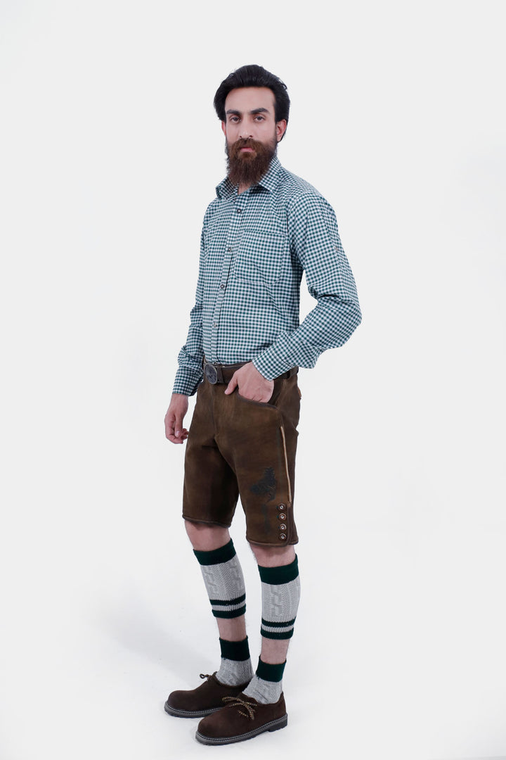 Full-body side view of the man wearing the Mahler Lederhosen. The lederhosen feature a traditional design with buttons along the side and are paired with green and white knee-high socks and brown shoes.