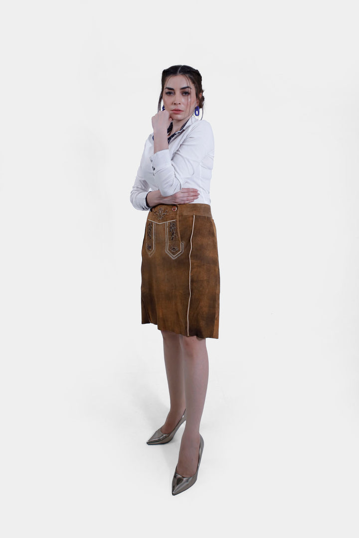 A woman posing in the Marianna Lederhosen Skirt, front view. The skirt's intricate embroidery and button details on the waist are clearly visible.