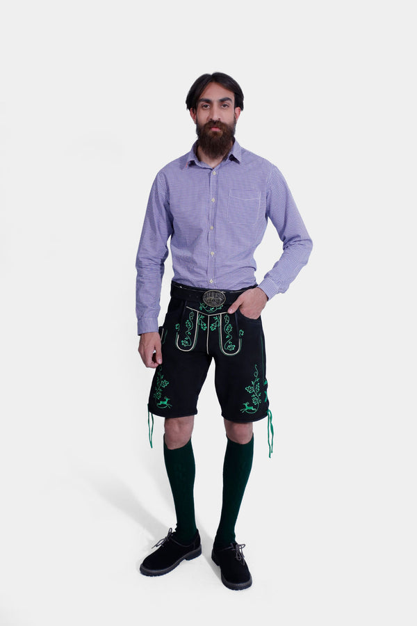 Man wearing the Melk Abbey Lederhosen Outfit, featuring a purple checkered shirt, black leather lederhosen with green embroidery, green knee-high socks, and black shoes. trachten lederhose herren​ , lederhose herren tracht​