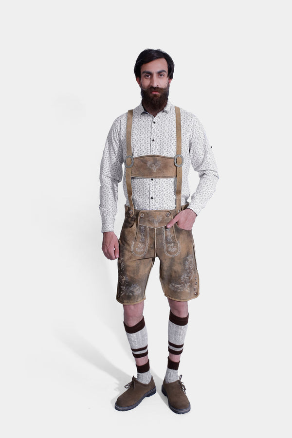 Front view of a man wearing Mozart Lederhosen with hands in pockets, showcasing the intricate embroidery and traditional Bavarian design. He is also wearing a white patterned shirt and beige shoes. lederhosen herren kurz, trachten lederhose herren kurz