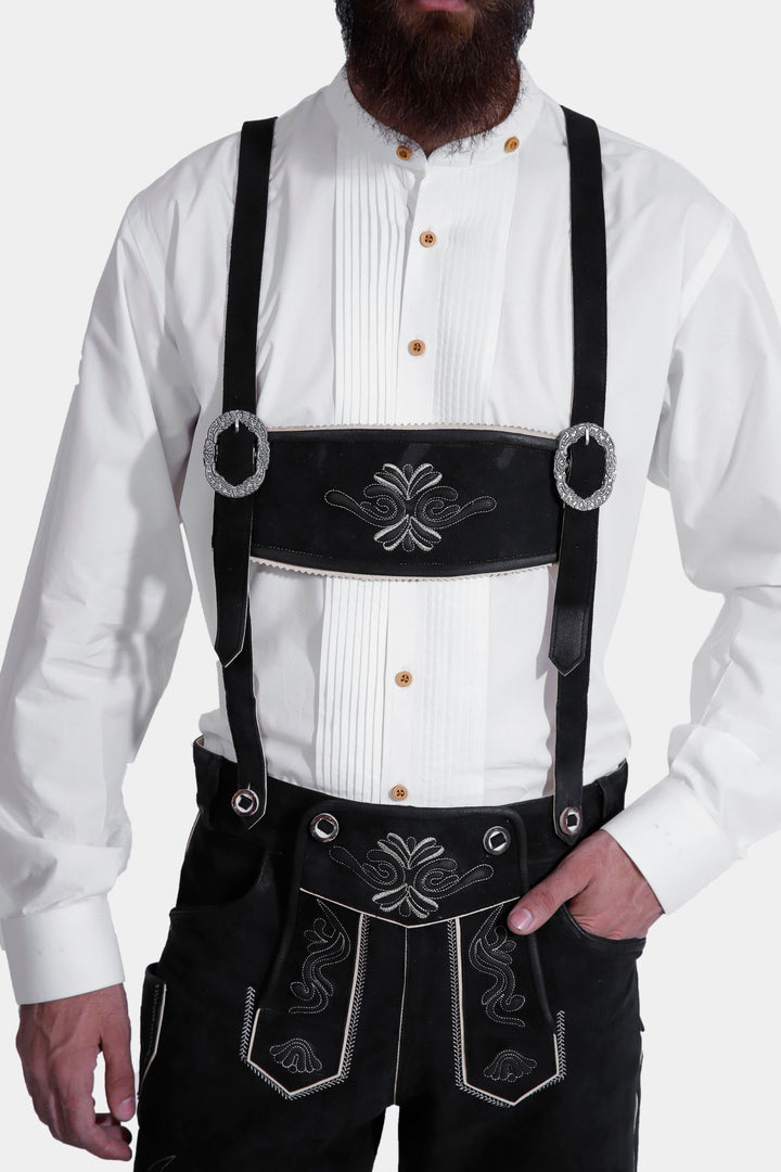 Frontal view of traditional lederhosen with Alpine decorative elements, worn with a pristine white shirt and brown casual shoes.