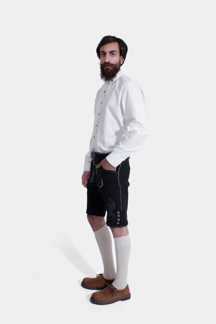 Authentic Oktoberfest clothing, a man models black lederhosen with a luxurious texture and rich embroidery.