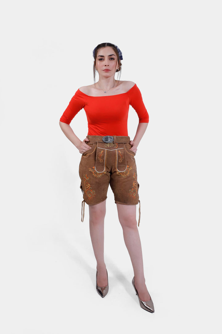 Full-body front view of a woman modeling Queen Victoria Lederhosen, showcasing knee-length shorts with natural-tone embroidery and a red off-shoulder top. damen lederhose kurz​, kurze lederhose damen​