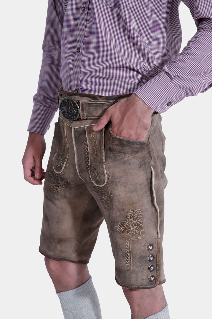 Close-up of Hofburg Lederhosen showcasing detailed embroidery, man's hand in pocket.