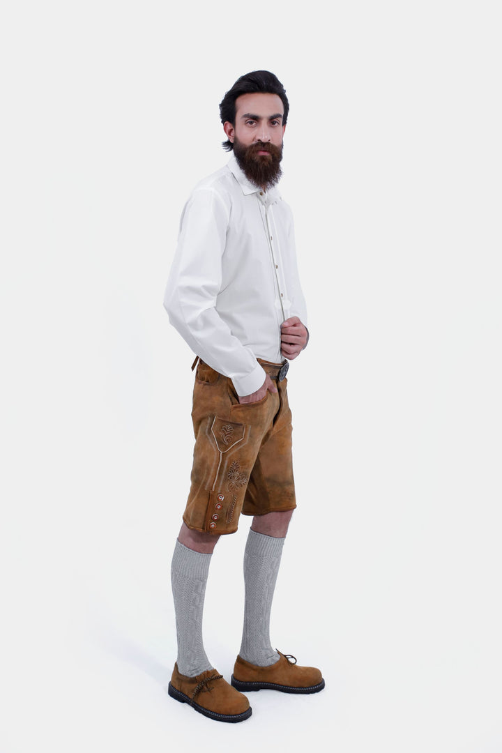 Side view of the man wearing the Rothenburg Lederhosen. The lederhosen feature detailed embroidery on the side and buttons along the knee area, paired with grey knee-high socks and brown shoes.