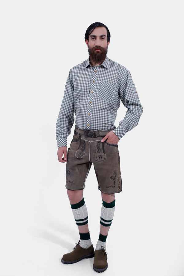 Full-body view of a man wearing Salzburg Fortress Lederhosen with a gray checkered shirt, standing with one hand in pocket, showcasing traditional Bavarian attire. lederhose tracht herren kurz