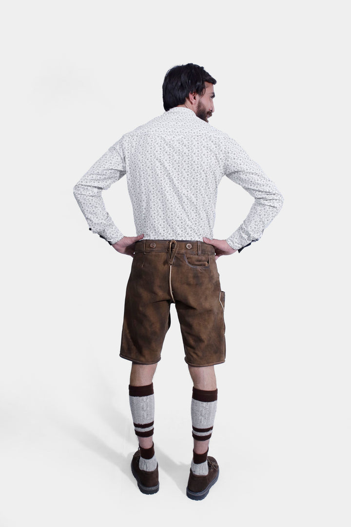 Back view of brown leather lederhosen, highlighting the fit and design details, worn by a man against a white background.