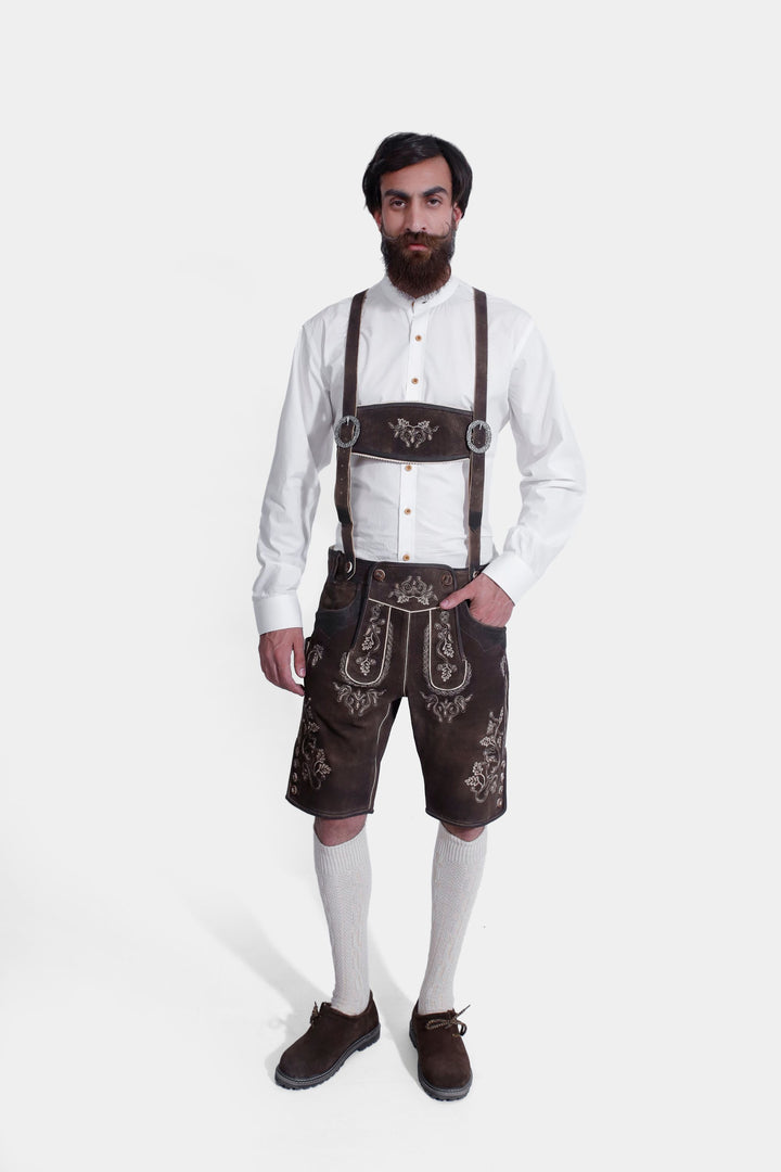 Full-body view of a model in Spiegel Lederhosen with suspenders, highlighting the ornate embroidery and traditional design, paired with a white shirt and knee-high socks.