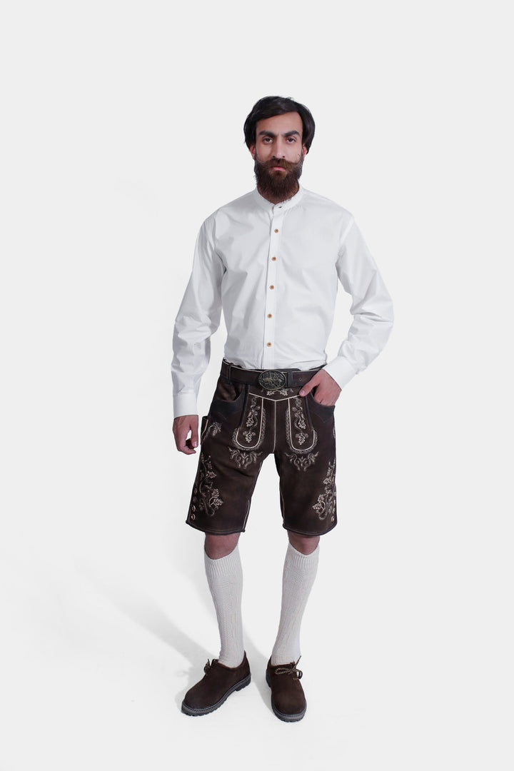 A man wearing a traditional white Bavarian shirt and brown Spieth Lederhosen outfit with intricate embroidery, standing against a plain white background. lederhose tracht herren kurz , trachten lederhose schwarz herren