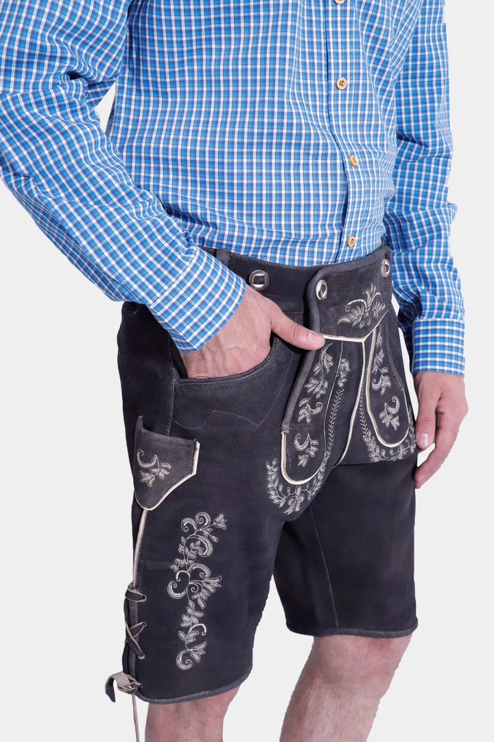 Side view of a man in Versailles Lederhosen with a blue checkered shirt, showcasing the embroidered details and side laces of the traditional leather shorts.