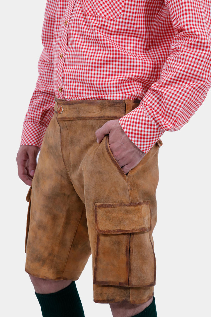 Close-up of a man wearing Wagner Cargo Lederhosen with a red checkered shirt, showcasing the detailed design and side pockets of the light brown leather shorts.