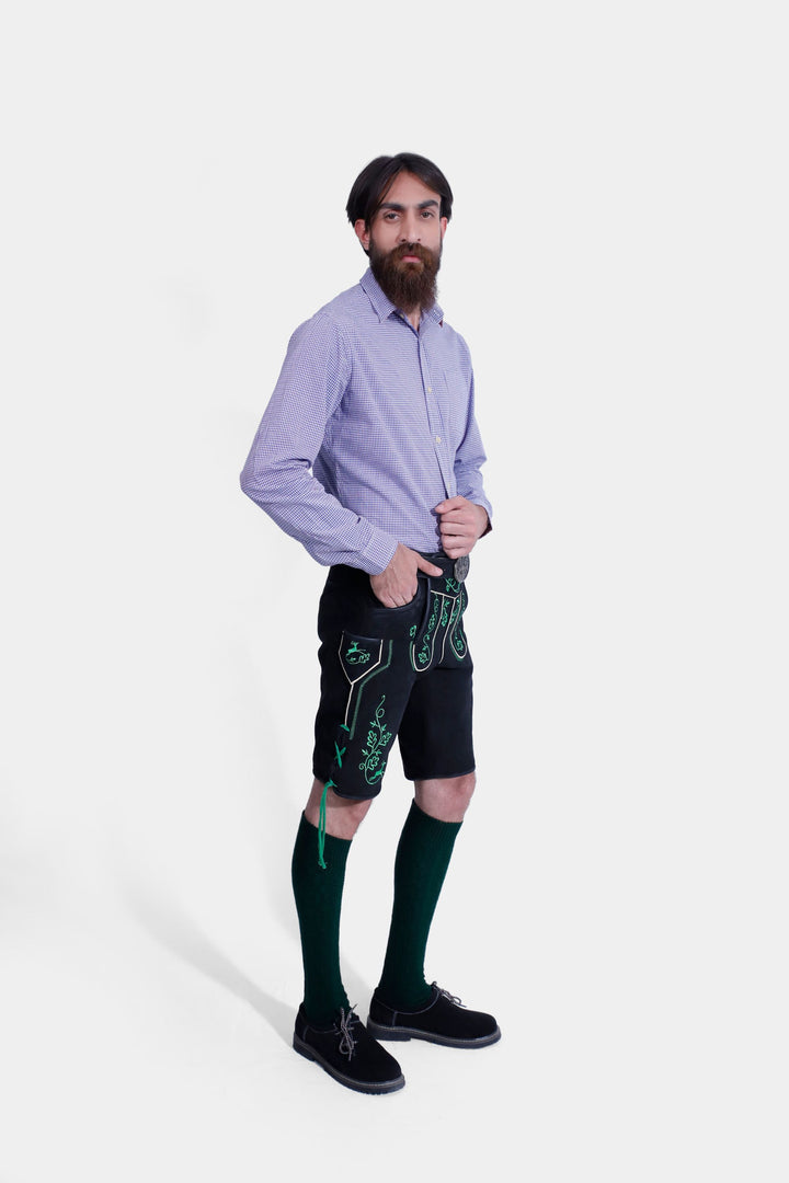 Full-length view of a man in black Zwinger Lederhosen and purple gingham shirt, showcasing traditional style with modern flair.