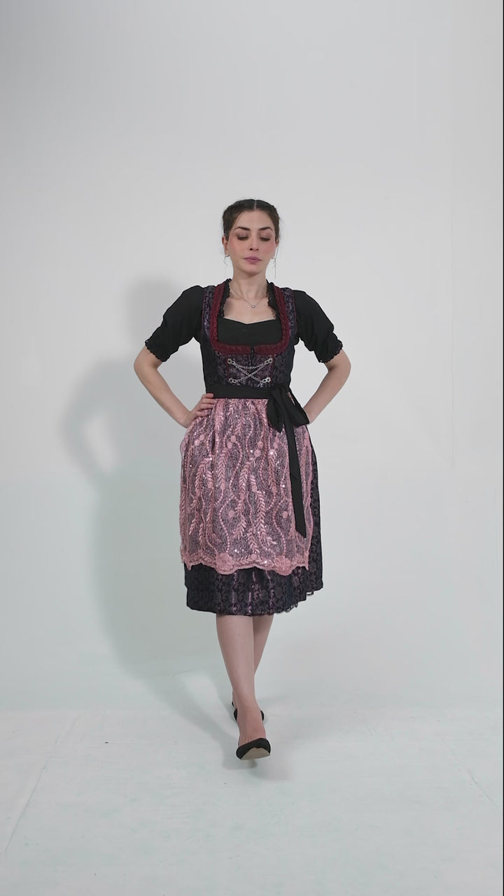 Video showcasing a model twirling in the Dirndl Franka, highlighting the intricate lace details on the apron and the sparkling embellishments on the bodice, set against a plain background to emphasize the outfit's elegance.