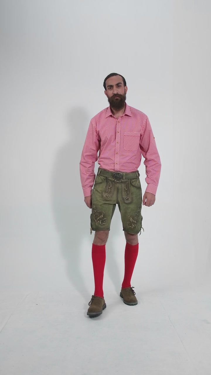 Video showing a man wearing traditional Heidelberg Lederhosen. He pairs the greenish-brown leather shorts with intricate embroidery and embellishments with a red and white checkered shirt. The outfit is completed with bright red knee-high socks and brown shoes. The man poses in various angles, highlighting the detailed craftsmanship and design of the lederhosen, including side and back views.