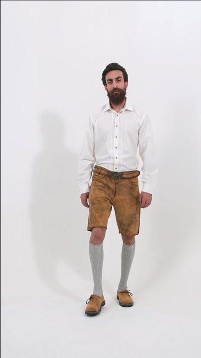 A video showcasing the Rothenburg Lederhosen outfit from every angle. The model, a man with a beard, wears light brown leather lederhosen paired with a white shirt featuring wooden buttons. The video captures detailed close-ups of the embroidery, buttons, and pockets, as well as full-body views from the front, back, and sides. The model completes the look with grey knee-high socks and brown shoes, presenting the traditional design and craftsmanship of the Rothenburg Lederhosen.