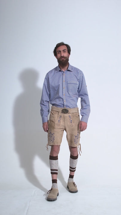 Video showing a 360-degree view of the beige-colored Mookie Lederhosen Outfit worn by a man in a blue checkered shirt and beige-colored shoes, highlighting the detailed craftsmanship, embroidery, and features of the traditional Bavarian leather shorts.