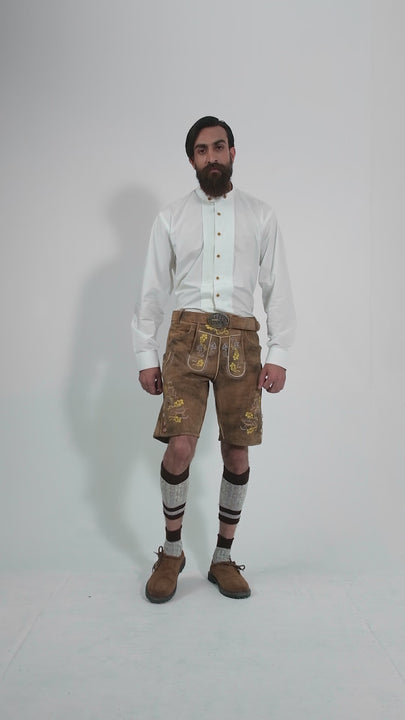 A video showcasing a man modeling Leavenworth lederhosen from different angles. The video highlights the intricate embroidery, traditional design, and details of the lederhosen, paired with a white shirt and brown shoes.