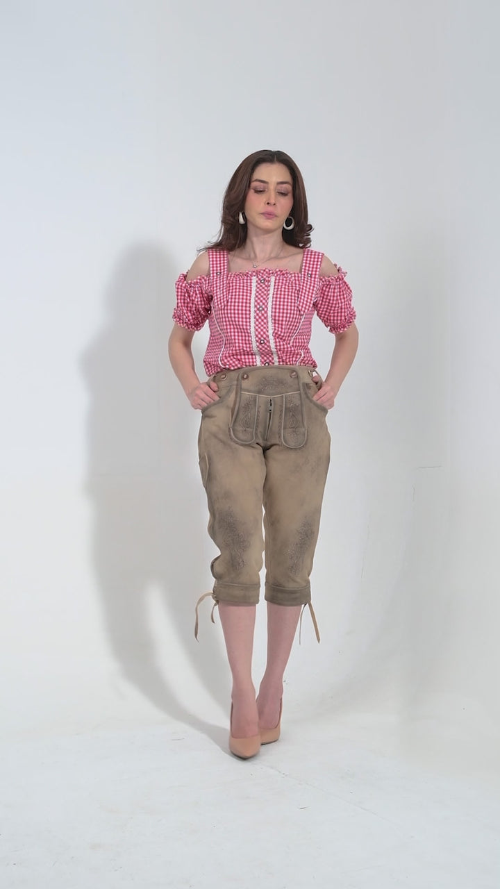 Video showcasing the Liv Tyler Lederhosen for women in  beige brown color. The video highlights the premium goat suede leather material, intricate natural color embroidery on the bib and legs, two front pockets, a side knife pocket, and the stylish brown horn buttons on the bib and cuffs. The adjustable waistband at the back ensures a snug fit. Note that matching belts and suspenders are not included, allowing for personalized styling.