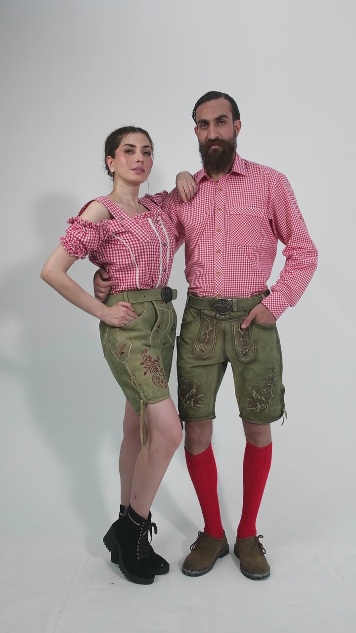 A video showcasing couple wearing traditional German outfits. The woman is dressed in a red and white checkered off-shoulder top with Olive embroidered shorts. The man is in a matching red and white checkered shirt, olive embroidered shorts, red knee-high socks, and brown shoes.